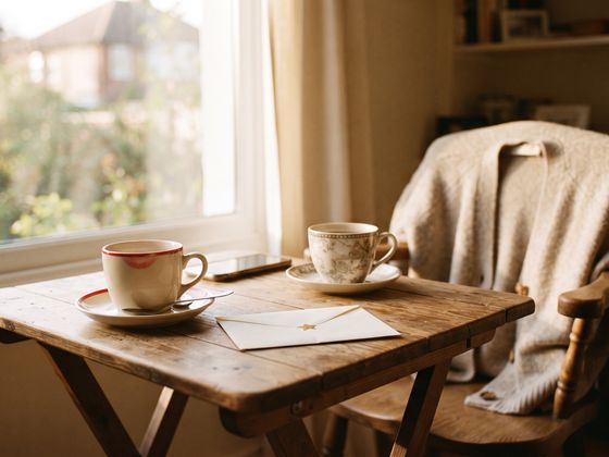 Two cups of tea and a letter by a window